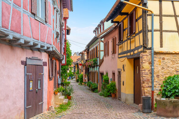 Fototapeta na wymiar A narrow cobblestone alley of colorful half timber buildings in the medieval Alsatian village of Eguisheim, France.