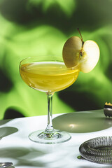 Apple pie alcoholic cocktail beverage with vodka, apple liqueur, cinnamon syrup.. Light green background, hard light, shadow pattern