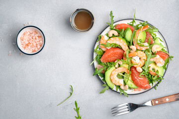 Fresh salad with shrimps, avocado, grapefruit, arugula and cashews. Gray kitchen  table background, top view