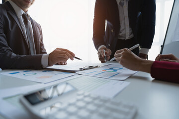 Group of Asian business people working on charts and finances Business development team meeting to set strategies to increase revenue for the business brainstorming graph analysis.