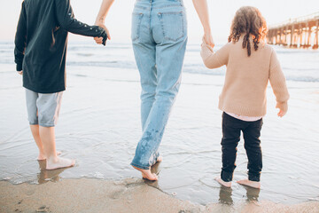 mom and children walking on the beach in low tide - obrazy, fototapety, plakaty