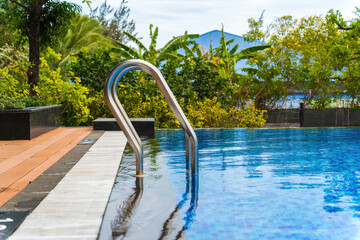 Metalic inox handrails at swimming pool. Waterpool and blue water. Relax concept