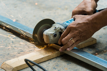 Close-up of man's hand using iron cutter in the workplace, fastening the iron canopy frame with spark