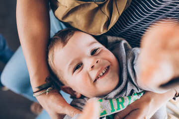 portrait of a child laughing up at the camera in his mother's lap