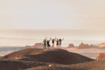 Group of happy tourists stands with open arms at desert view point - obrazy, fototapety, plakaty