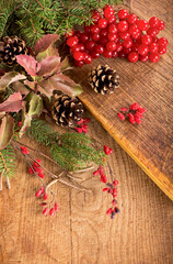 branches of holly, pine cones, mountain ash berries on wooden background
