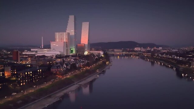 Refelection in the Rhine river of the ultamodern Roche Towers illuminated by the setting sun in Klein Basel in Switzerland. Drone dolley shot