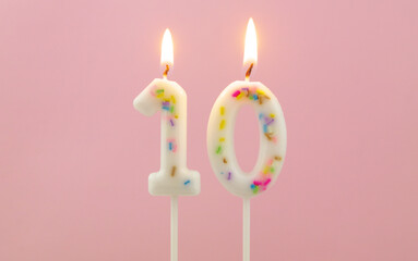 White decorated burning birthday candles on pink background, number 10