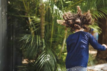 Preschool girl playing in pretty tropical kindergarten garden