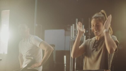 A group of three friends talking and smiling after a successful training session with stationary bike. Giving high five to each other after workout session
