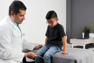 Professional specialist pediatrician doctor and patient 7-year-old Latino brown-haired boy are in consultation to check their eyes, mouth and throat to diagnose any disease in the office