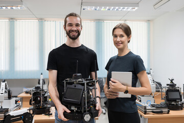 Portrait of male and female engineers holding AI Robot and Artificial Intelligence of Things service robot in the manufacturing automation and robotics laboratory class room