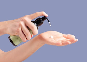 Moisturizer, skincare and hands with a bottle for cream isolated on a blue background in studio. Beauty, cosmetic and woman with lotion or sunscreen in palm for moisture, treatment and grooming