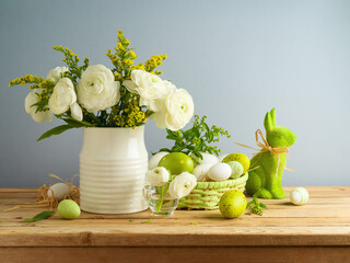 Easter holiday still life with white flowers bouquet and Easter eggs decoration on wooden table over gray background