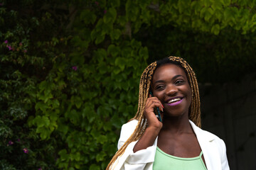 Fototapeta premium Happy Young Black woman talking on the phone outdoors. Copy space.