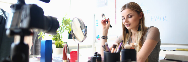 Young female blogger is recording tutorial video for blog about cosmetics