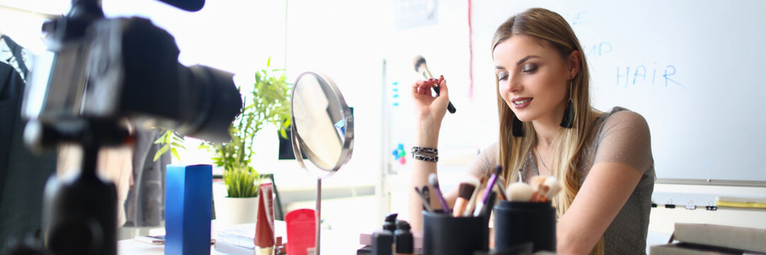 Young female blogger is recording tutorial video for blog about cosmetics