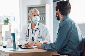 Fototapeta na wymiar Consultation, covid and doctor with a man for healthcare, medical attention and service. Medicine, support and consultant with a face mask for virus while talking to a patient about health results