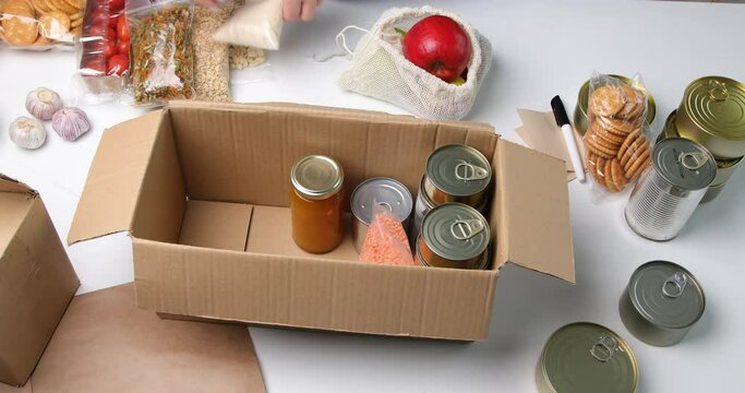 Food donations with pasta, rice, oil, peanut butter, canned food, jam and other  on light background, top view.  Food donations or delivery concept.