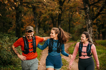 Young male and female embraced joggers walking and resting after running in the forest.