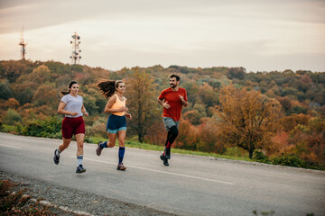 A group of happy athletes enjoying running and communicating while jogging in nature. Copy space