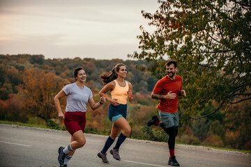 A small group of joyful athletes enjoying running and communicating while jogging in nature.