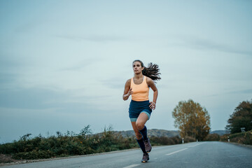 Female athlete with long hair running outdoors early in the morning during her cardio routine.
