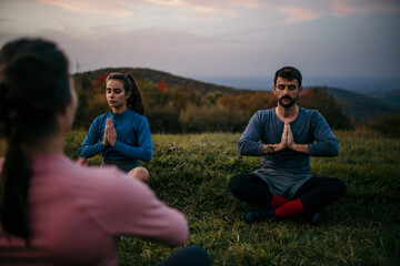 Three people meditating outdoors. Two people followed a guided meditation from a female yoga tutor.