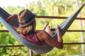 Woman relaxing in hammock in vacation. Woman relaxing with coffee in hammock in vacation on tropical island in Thailand.