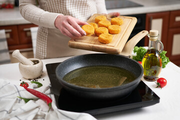 Woman puts cheese balls into frying pan with hot cooking oil