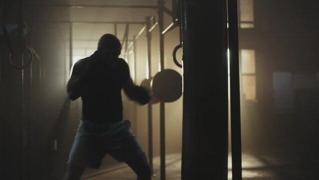 Man exercising with punching bag at the gym in slow-motion