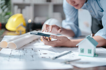 Fototapeta premium Drawing construction plan remodel and renovate and old house at meeting team engineer desk in office building. Using calculator