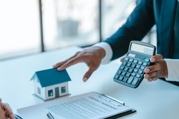 mortgage loans calculate numbers on calculator, realtor suggestion a new house model assisting client to sign contract agreement with insurance to happy living building, concerning mortgage loan offer