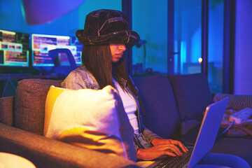 Woman, hacker and programmer typing on laptop in home at night in neon to hack software....