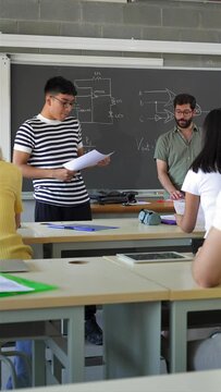Latin American college student presenting a project reading a composition to classmates and teacher at High School classroom - Vertical Video