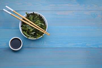 Fresh laminaria (kelp) seaweed served on light blue wooden table, flat lay. Space for text - obrazy, fototapety, plakaty