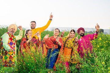 Punjabi sikh family doing bhangra dance in agriculture field celebrating Baisakhi or vaisakhi festival. People of punjab have fun, Culture of india.