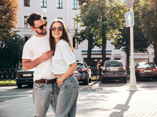 Smiling beautiful woman and her handsome boyfriend. Woman in casual summer jeans clothes. Happy cheerful family. Female having fun. Sexy couple posing in the street at sunny day. In sunglasses