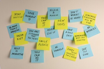 Paper notes with life-affirming phrases on white wall