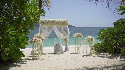 Beautiful Wedding event decoration beach sea tropical island sunset Germany. Set up arch decor flowers pattern coconut palm trees sand sunlight. Setting outdoor marriage detail table stage sky clouds.