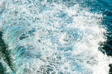 Waves on the sandy beach. Water background, blue sea water. Beautiful texture of sun glare on the...
