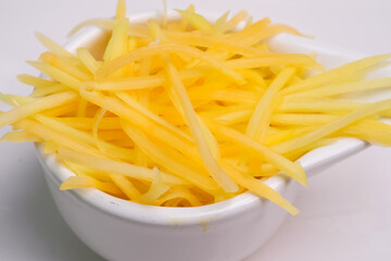 Half-ripe papaya grated in a bowl ready to cook. Raw papaya slices.