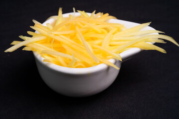 Half-ripe papaya grated in a bowl ready to cook. Raw papaya slices.