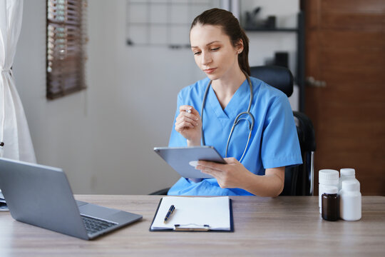 Portrait of a female doctor using a tablet computer and a document analyzing a patient's condition before treating.