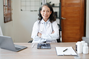 Portrait of a female doctor using a computer and a document analyzing a patient's condition before treating.