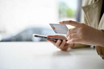 a woman's hands holding a smartphone and a credit card at the table. mobile banking