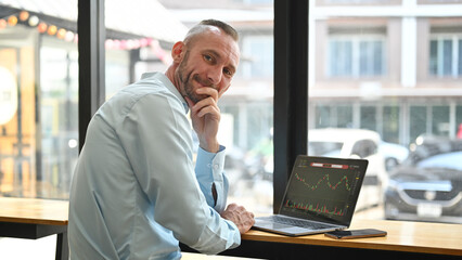 Fototapeta premium Caucasian businessman trader investor using laptop with financial chart trading online investment data on monitor