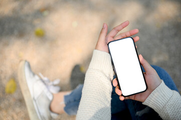 A woman's hand holding a smartphone mockup over blurred street in background