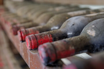 Chianti wine from Sangiovese grapes aging in old wine bottles at a vineyard in the famous wine producing Chianti Classico Region of Tuscany, Italy - obrazy, fototapety, plakaty