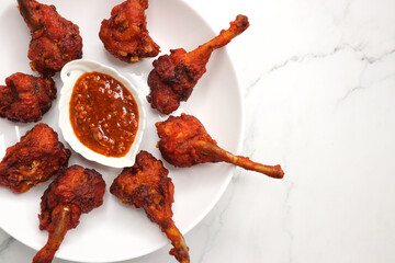 Chicken lollipop is an Indian style of Chinese appetizer. surved with schezwan chutney. Over white...